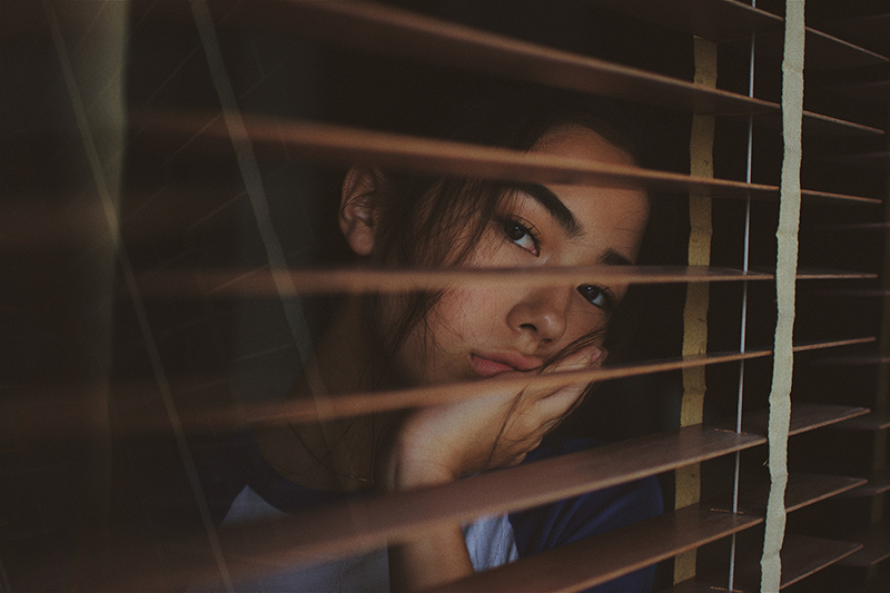 Female student going through homesick feelings while looking out the window