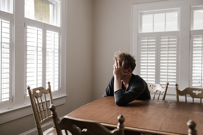 Young man feeling homesick in the dining room of a frat house