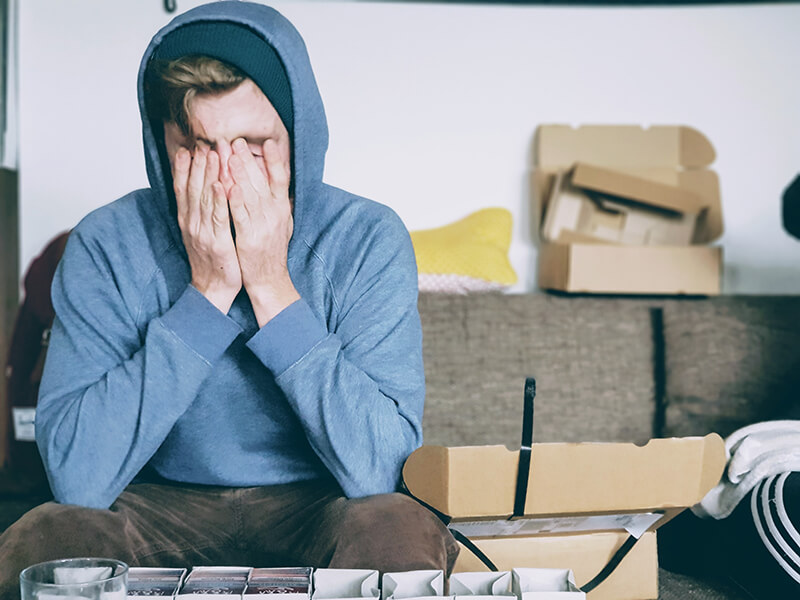 Male college student suffering burnout symptoms and covering his face