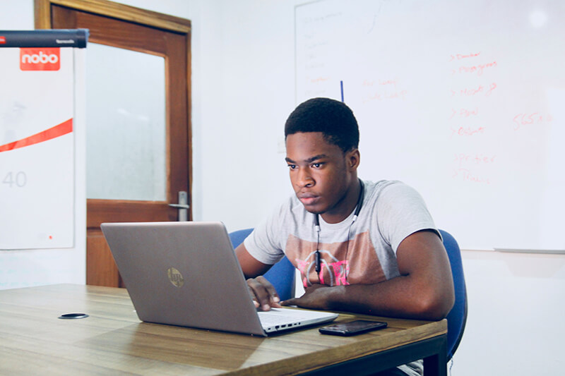 African American college student sitting in a classroom writing an argumentative essay