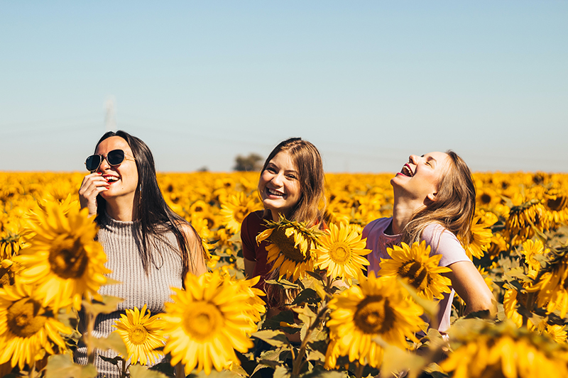 Female friends in a sunflower patch checking out a new place in college