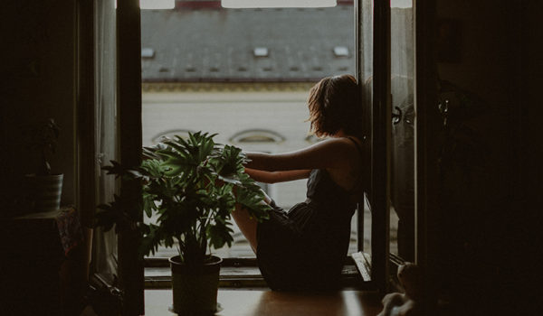 Young woman sitting in the window learning how to deal with homesickness