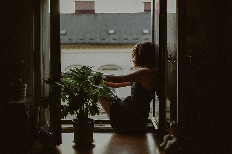 Young woman sitting in the window learning how to deal with homesickness