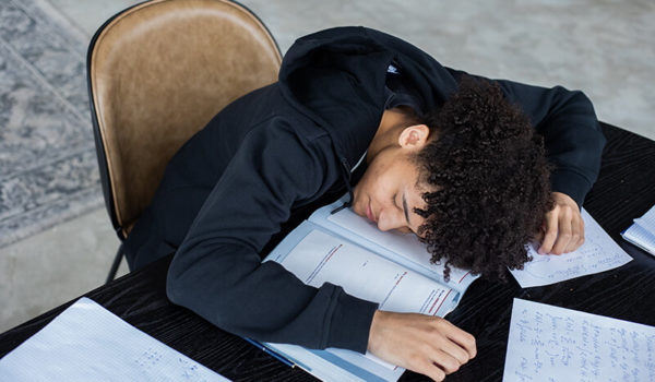 Male student with his head on the desk suffering from burnout syndrome