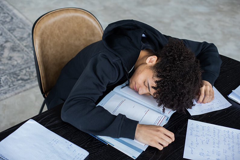 Male student with his head on the desk suffering from burnout syndrome
