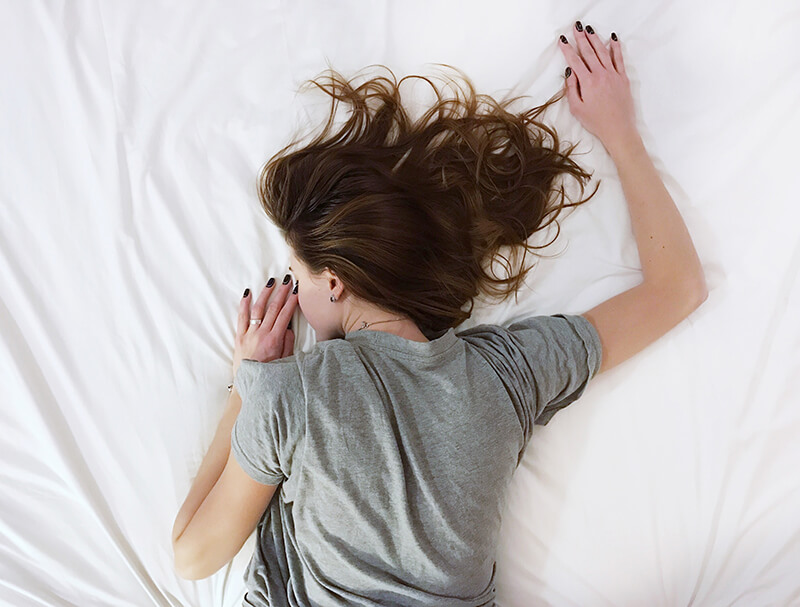 Female student laying in bed trying to escape her stressors