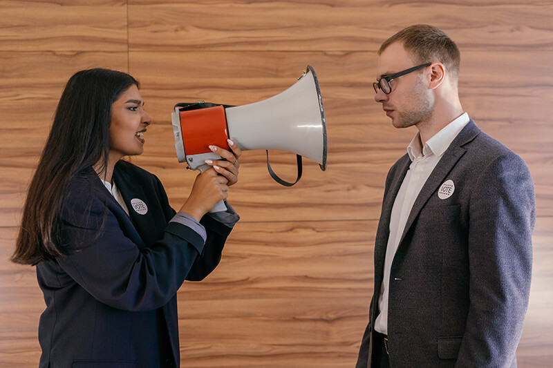 Female student presenting a persuasive speech to a friend with a megaphone