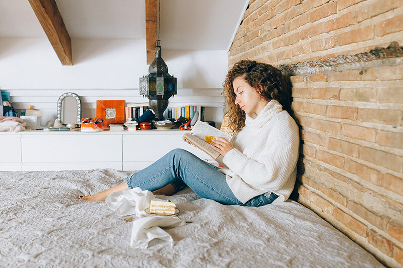 Female student taking some time to study in her dorm room bed