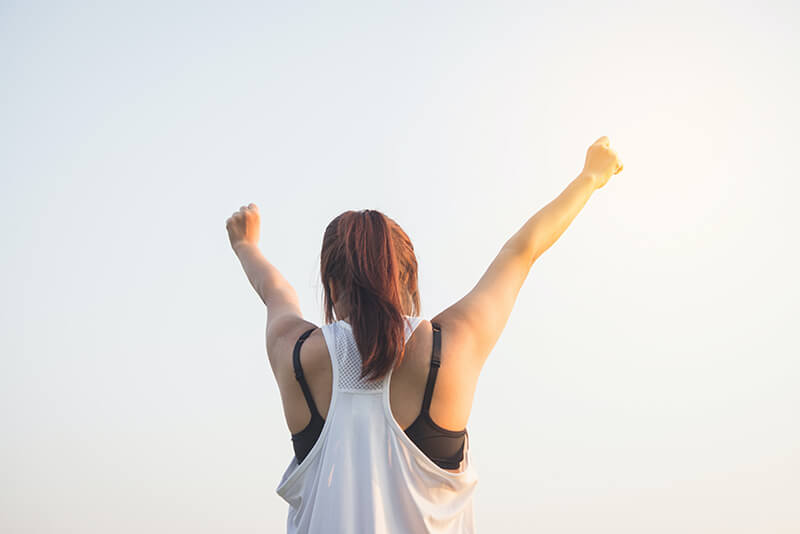 Female student in a tank top using running to practice self care