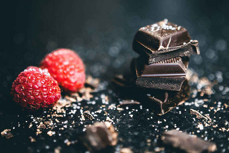 A healthy snack of dark chocolate and raspberries on a counter