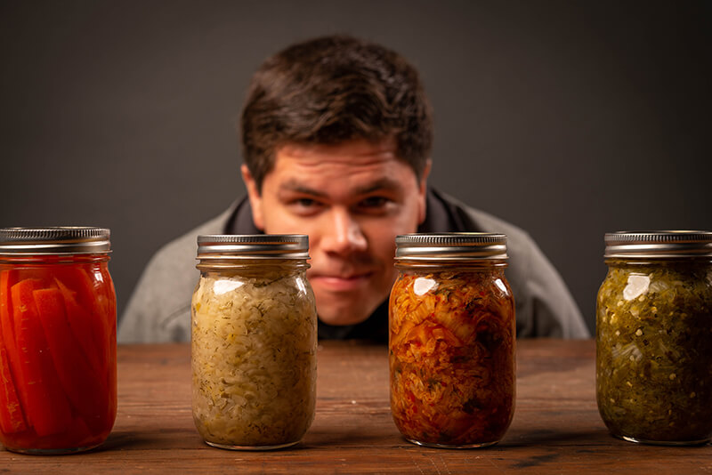 Male student looking at jars of fermented kimchi and superfoods