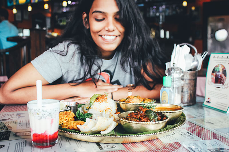 Female student in a restaurant eyeing a plate of junk food