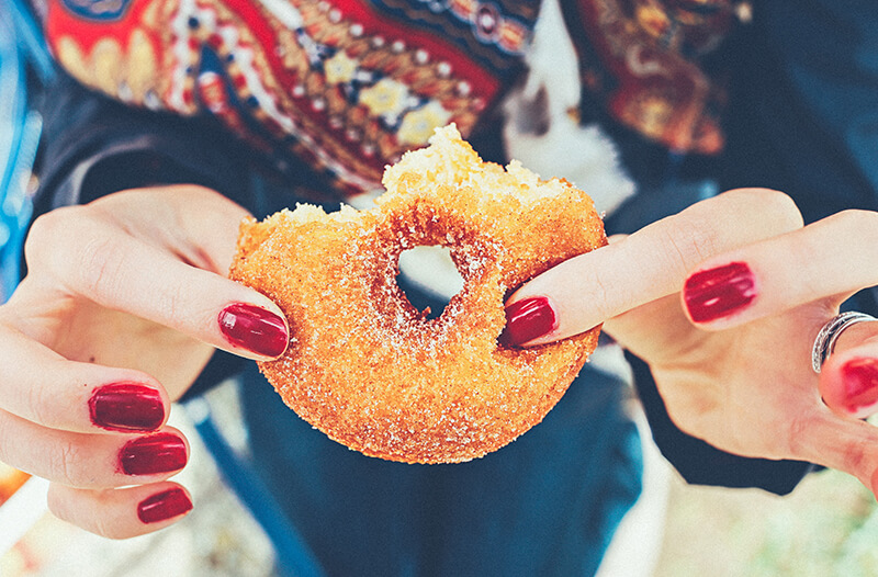 Female student holding junk food up in front of her face