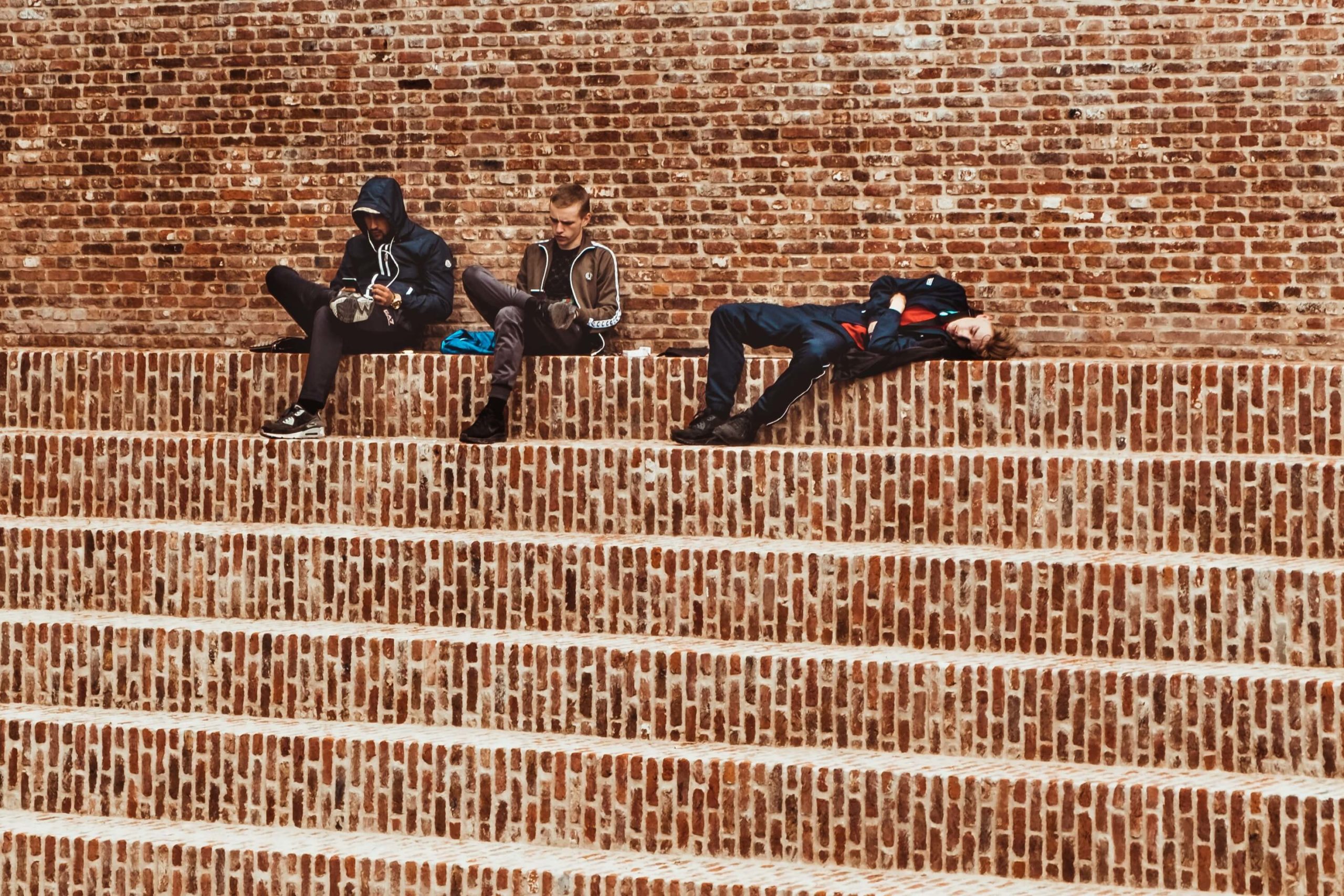 One of three male students asleep on stair steps due to senioritis