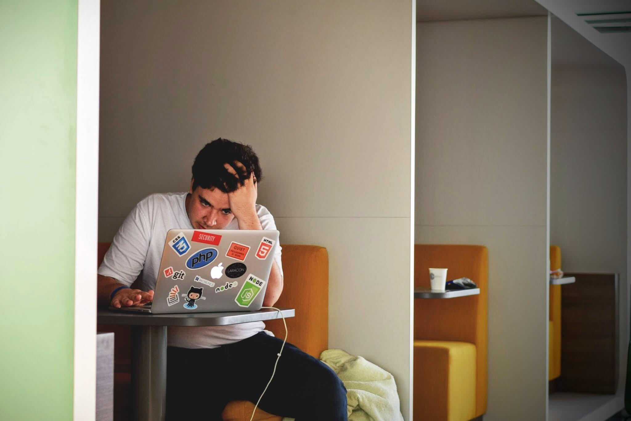 Male student with senioritis having a hard time while working on laptop