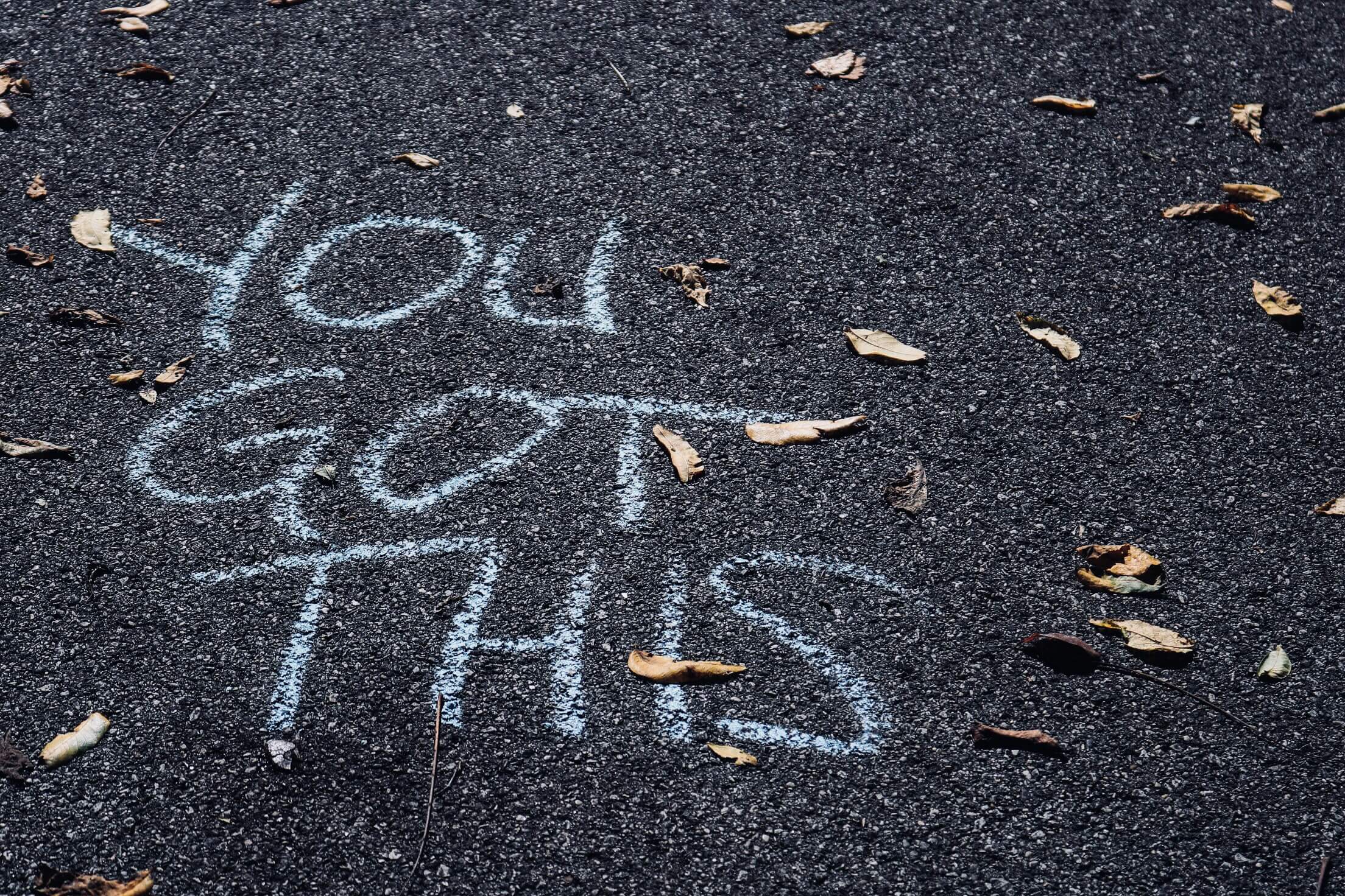 Motivational words “You got this” for students with senioritis written with chalk on an asphalt road