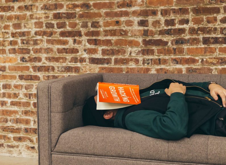 Male Student with senioritis is unable to stay awake while reading a book