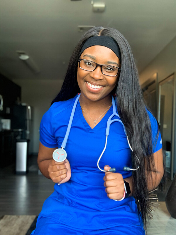 Mykyla Coleman in her blue scrubs with a stethoscope