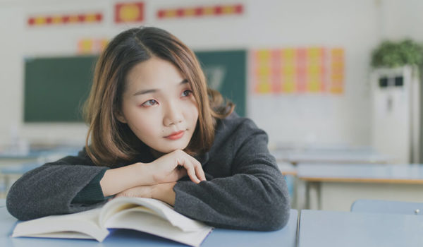 Female student pondering the reasons why is homework beneficial