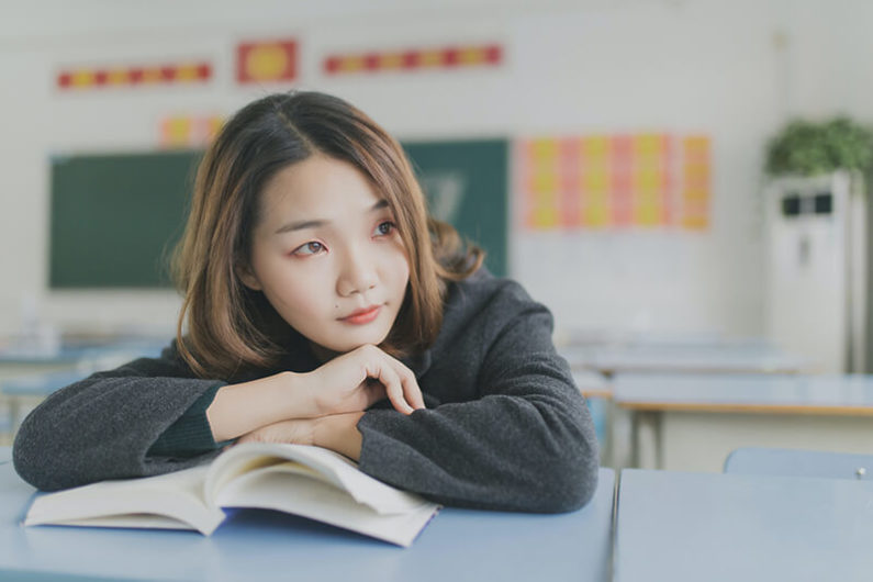 Female student pondering the reasons why is homework beneficial