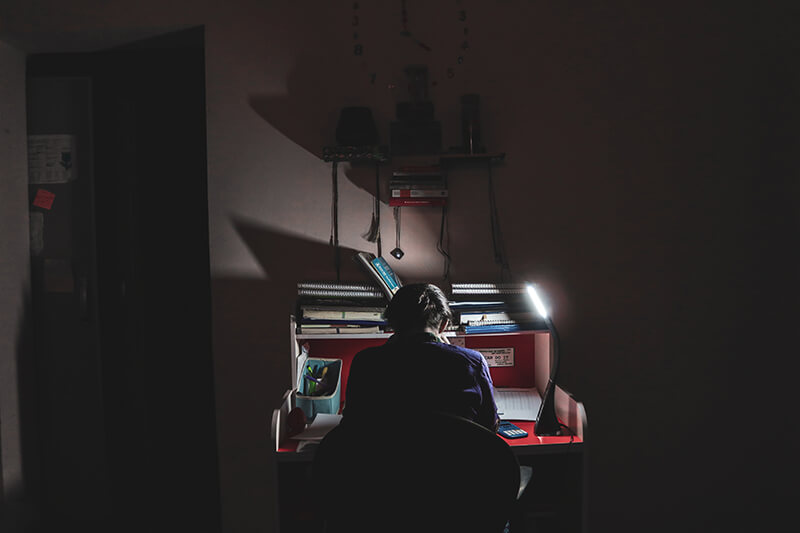 student curious about his assignment at night time in dark room