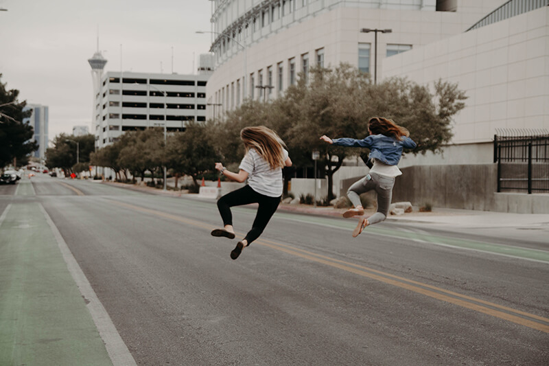 two friends jumping down a street and having fun