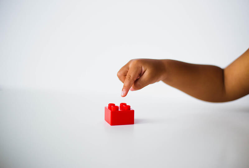 child playing with a red building block