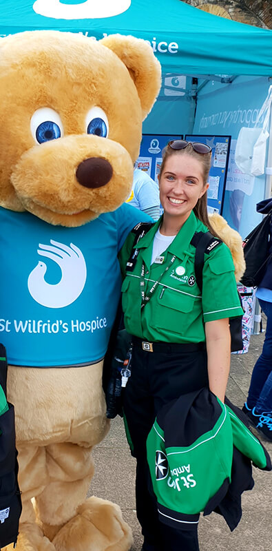 Paramedic Beth Franks on the job posing with a mascot bear