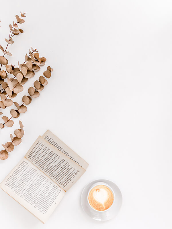 A clean layout of a book and a cappuccino