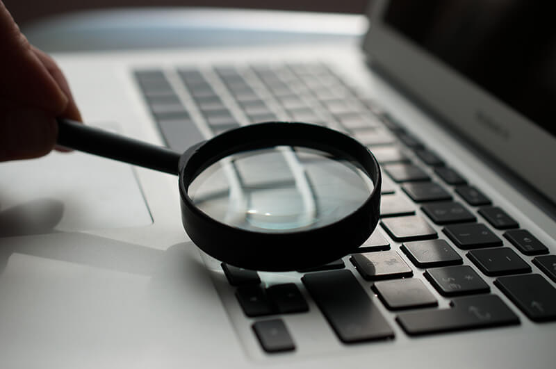 Magnifying glass on top of a keyboard to symbolize looking for facts
