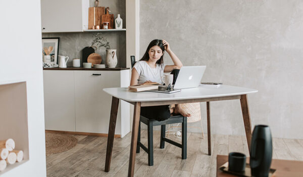 A student sitting at a desk learning how to write a rhetorical analysis essay on a laptop.
