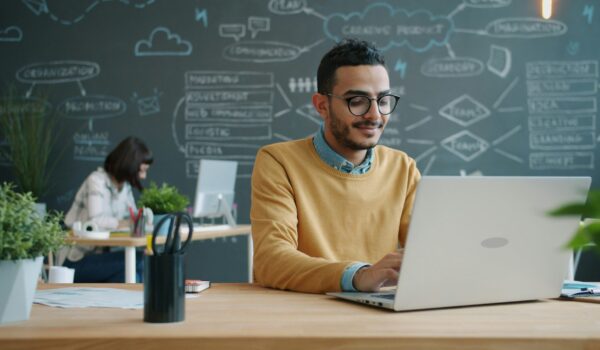 A student using AI writing tools on a laptop to learn how to make AI writing sound human.